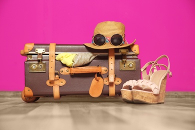 Photo of Suitcase packed for summer journey on floor near color wall