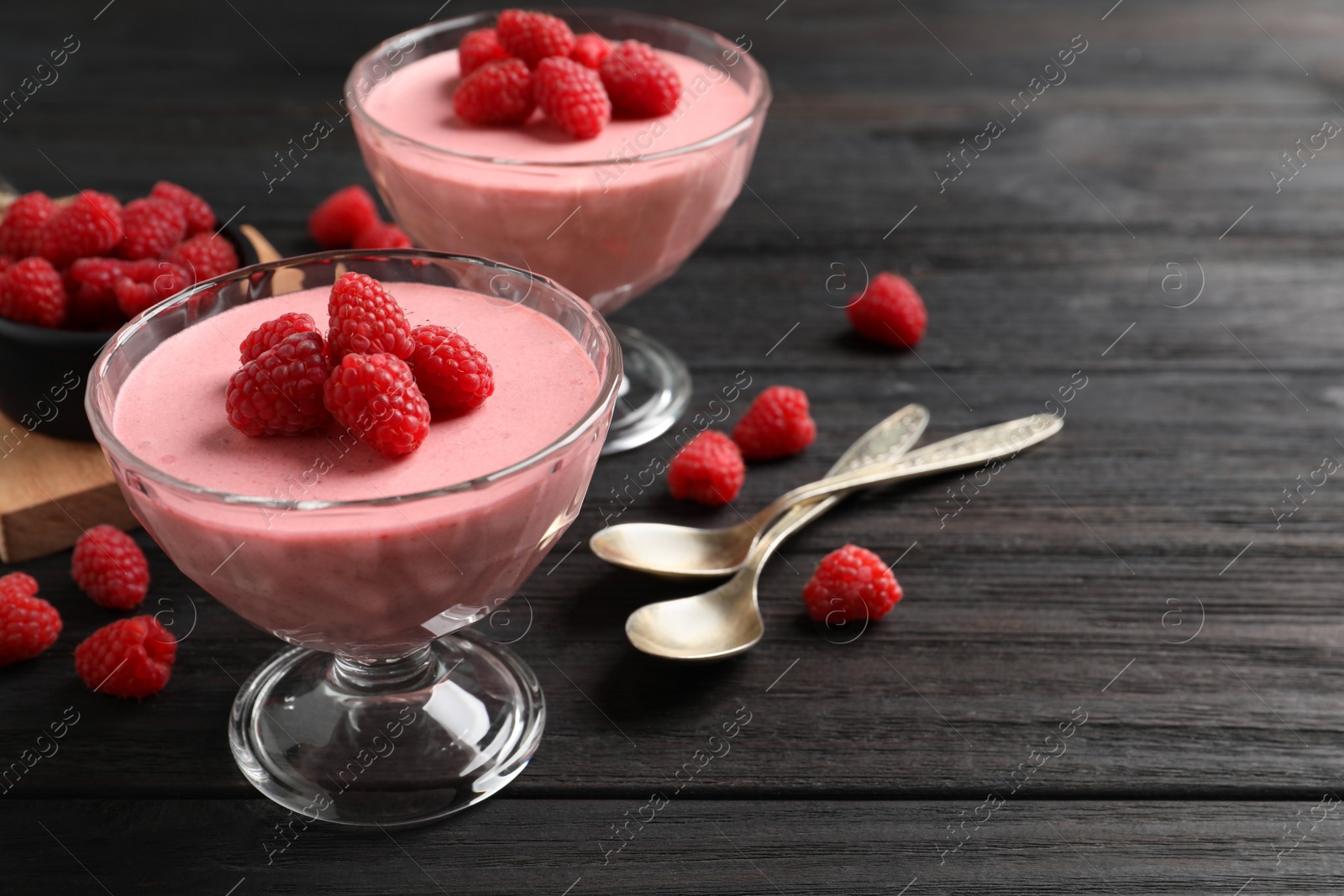 Photo of Delicious raspberry mousse on black wooden table, space for text