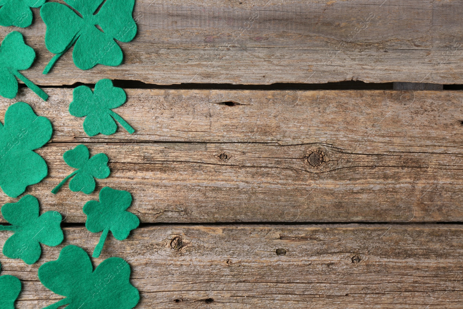 Photo of St. Patrick's day. Decorative clover leaves on wooden background, flat lay. Space for text