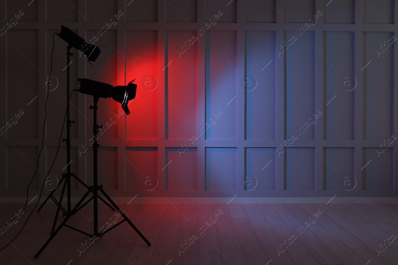 Photo of Bright red and blue spotlights near wall indoors, space for text