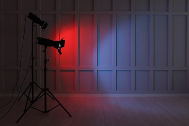 Photo of Bright red and blue spotlights near wall indoors, space for text