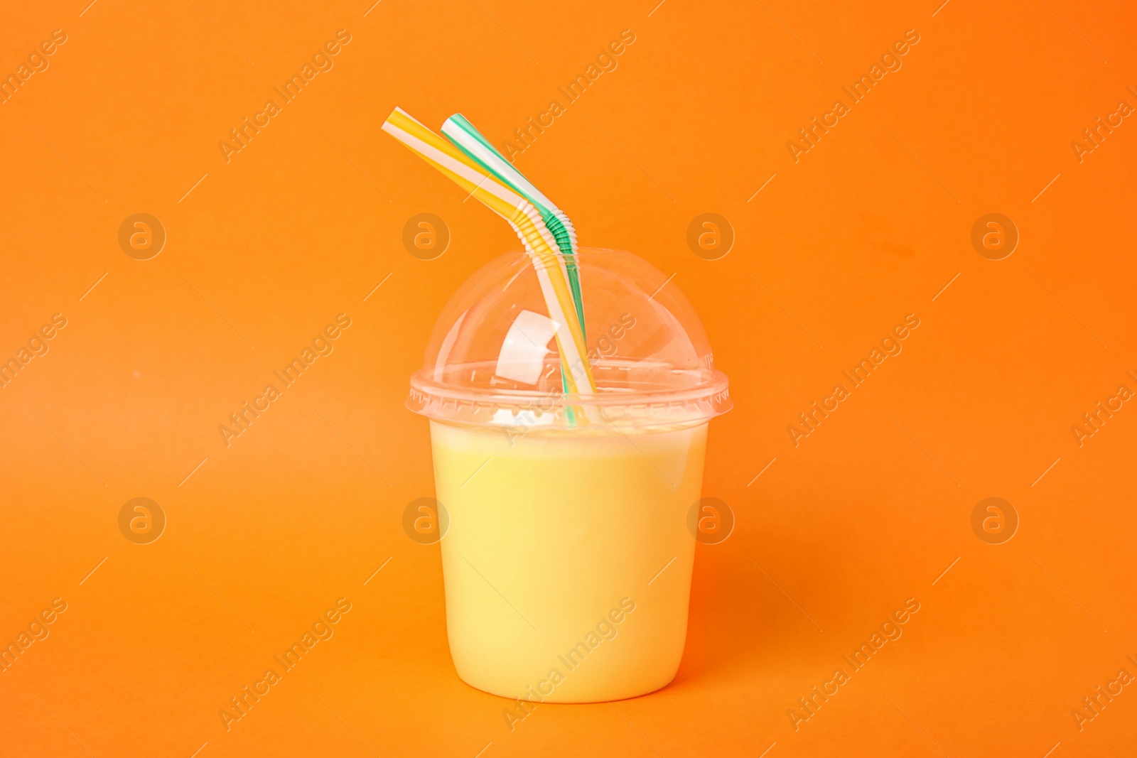 Photo of Plastic cup of tasty milk shake on color background