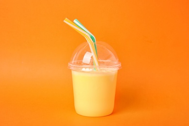 Photo of Plastic cup of tasty milk shake on color background