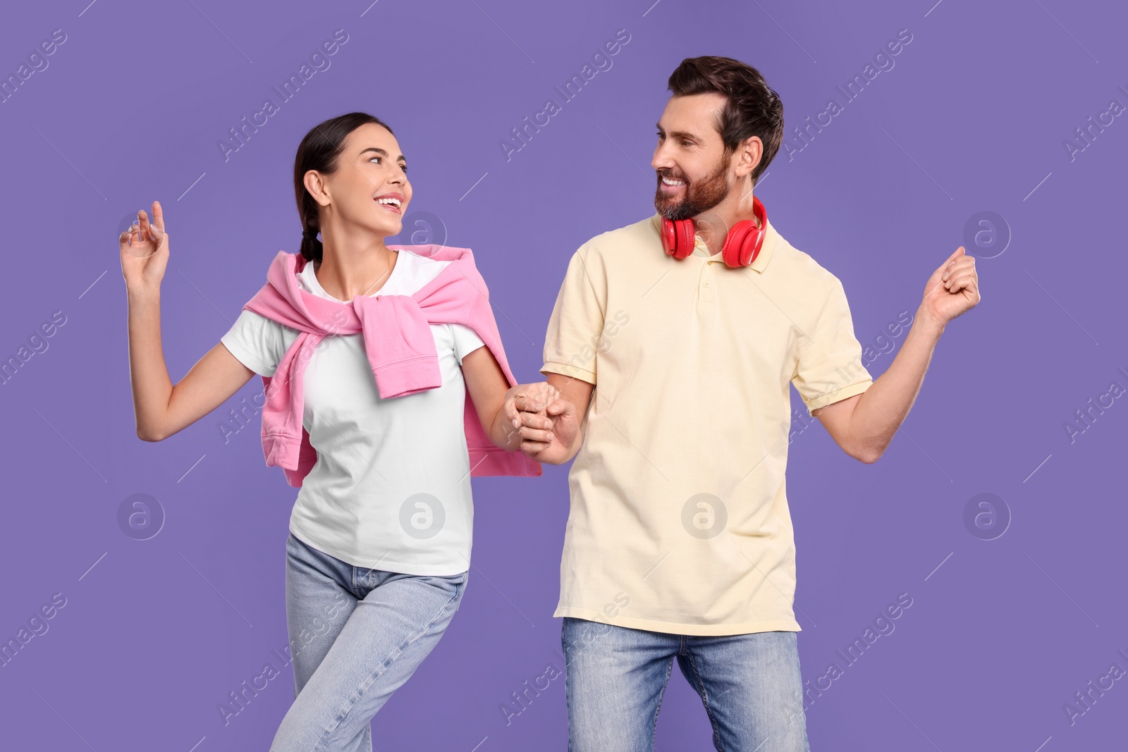 Photo of Happy couple dancing together on violet background