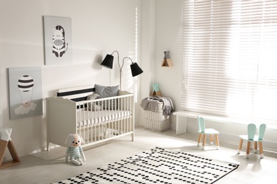 Photo of Cute baby room interior with crib and decor elements