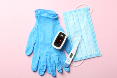 Photo of Flat lay composition with modern fingertip pulse oximeter and medical items on pink background