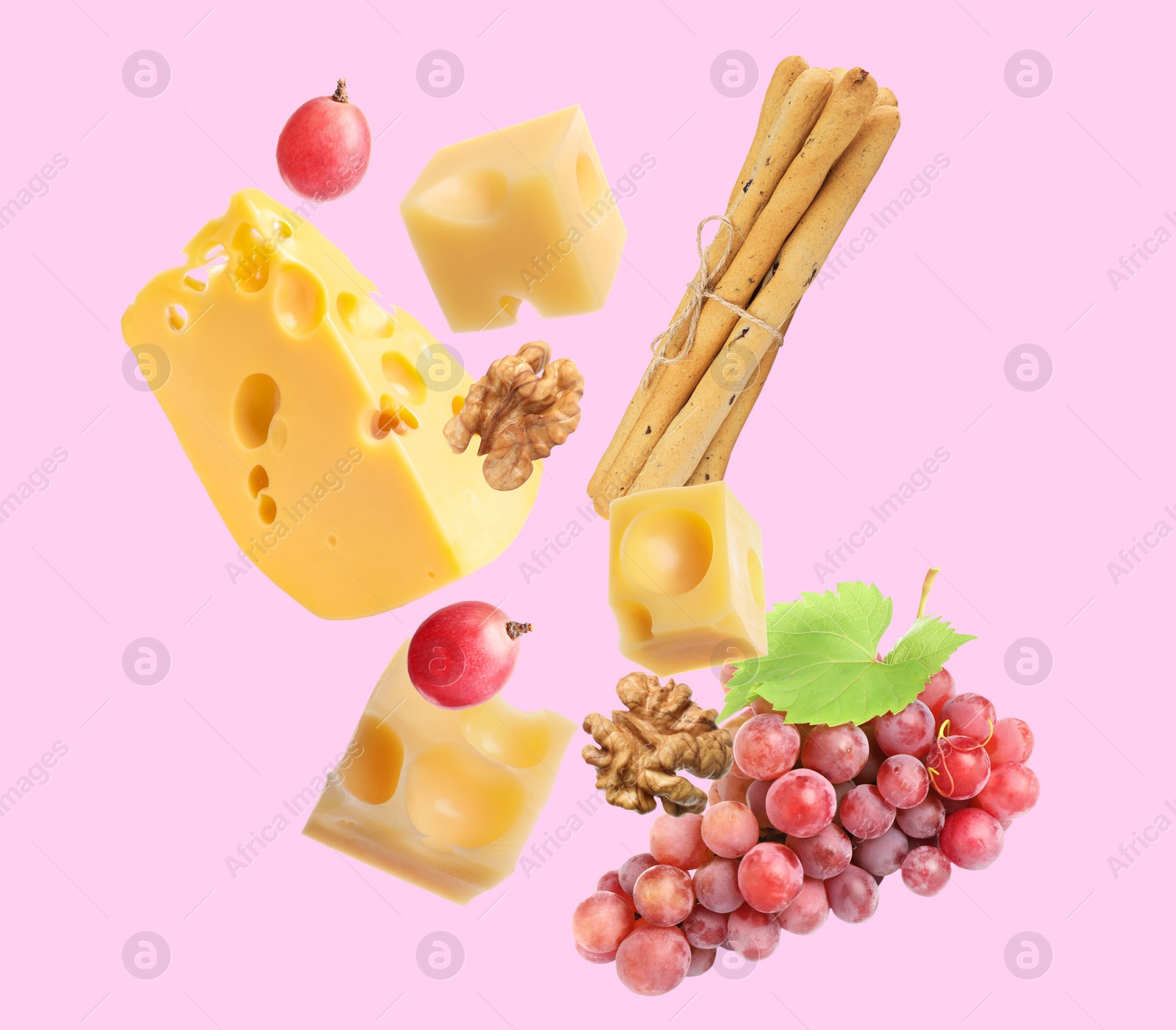 Image of Cheese, breadsticks, grapes and walnut falling against light pink background