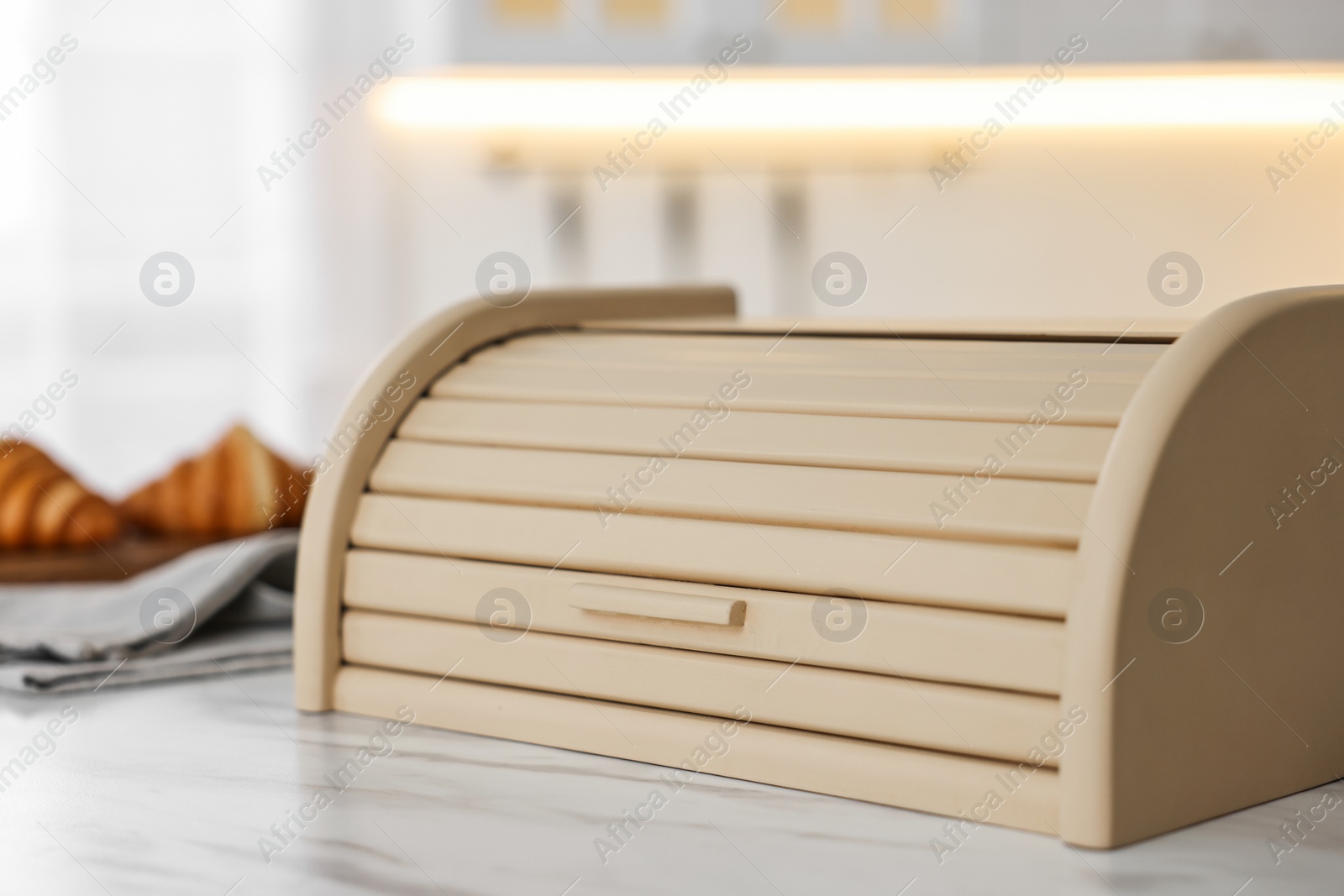 Photo of Wooden bread box on white marble table in kitchen, closeup