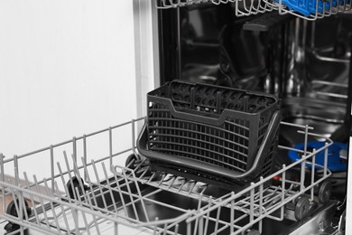 Photo of Open clean empty dishwasher in kitchen, closeup. Home appliance
