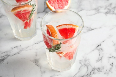 Photo of Glasses of infused water with grapefruit slices on marble table