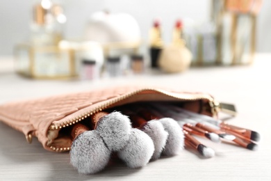 Photo of Cosmetic bag with makeup brushes on table