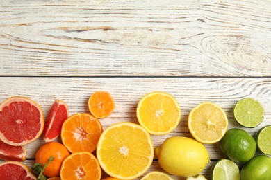 Different citrus fruits on wooden background, top view. Space for text