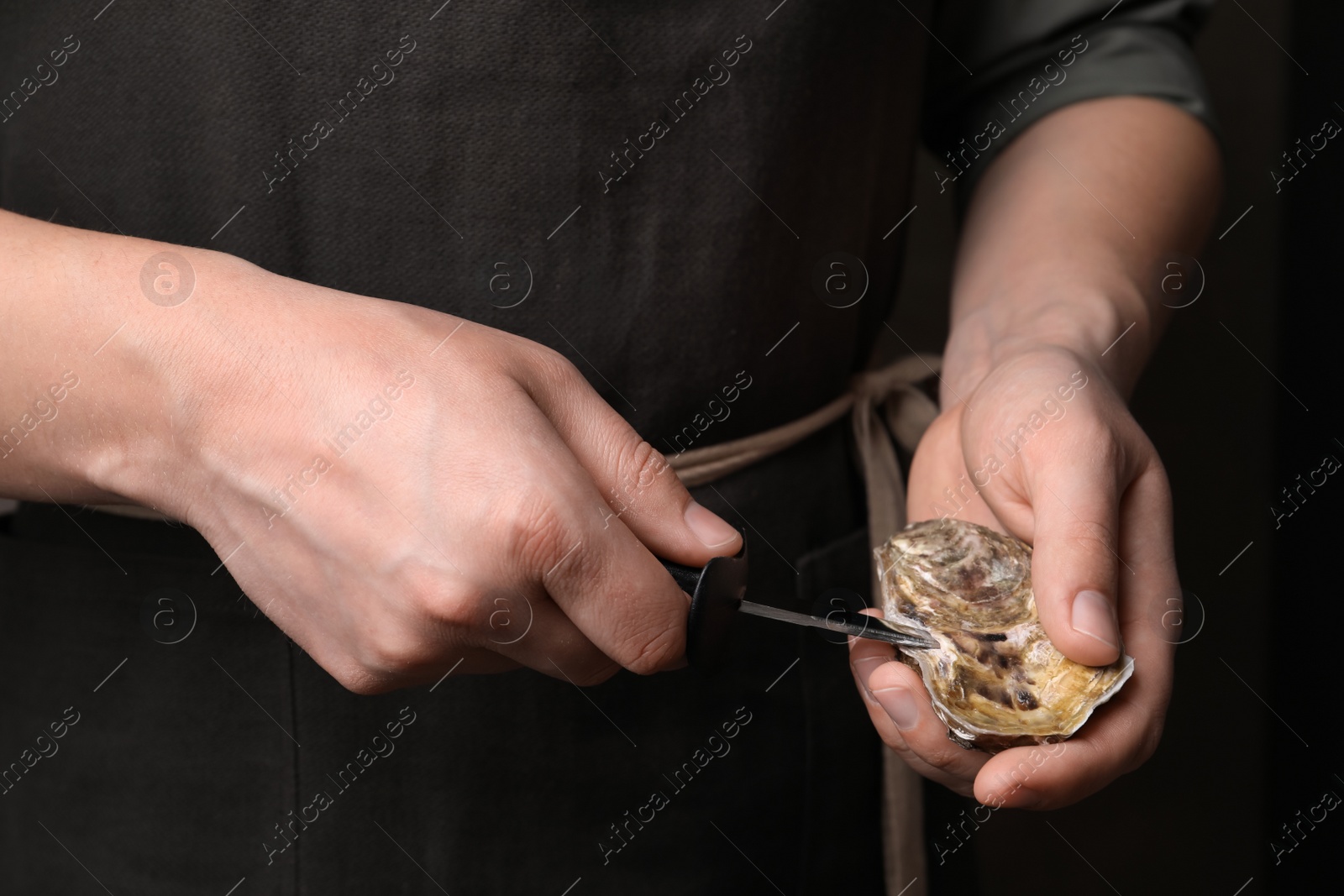 Photo of Man opening fresh oyster with knife, closeup