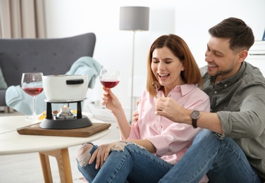 Photo of Happy couple enjoying fondue dinner at home