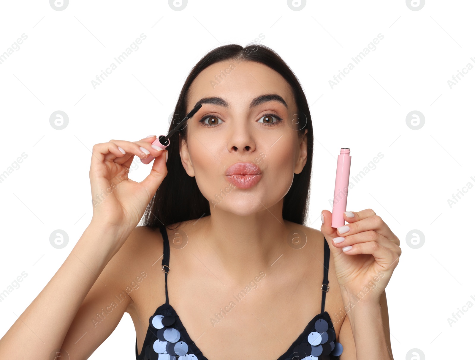 Photo of Beautiful young woman sending air kiss while applying mascara on white background