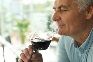 Photo of Senior man with glass of wine in restaurant. Space for text