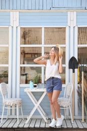 Photo of Young woman near white wooden table and gardening tools at home plant shop