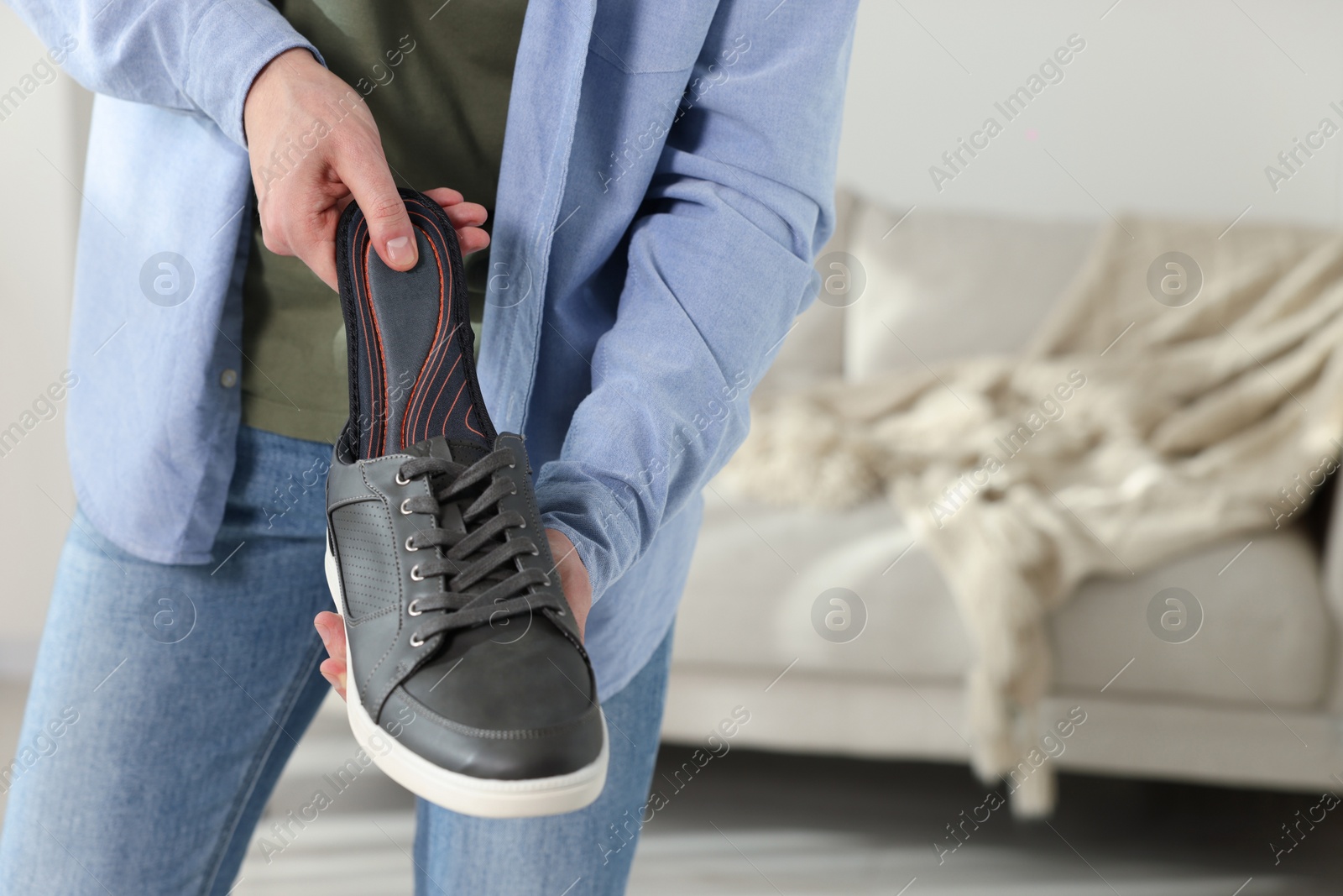 Photo of Man putting orthopedic insole into shoe indoors, closeup. Space for text