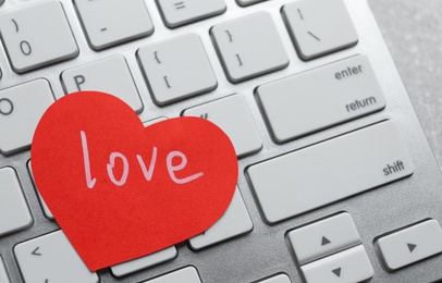 Paper heart with word LOVE on laptop, closeup