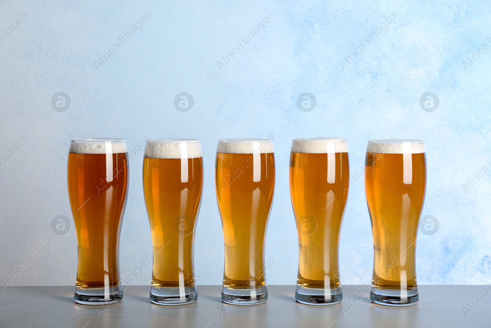 Photo of Glasses with beer on table against color background