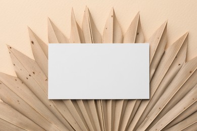 Photo of Blank business card and decorative plant on beige background, top view. Mockup for design