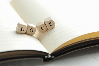 Image of Word Love made with wooden cubes on open notebook, closeup