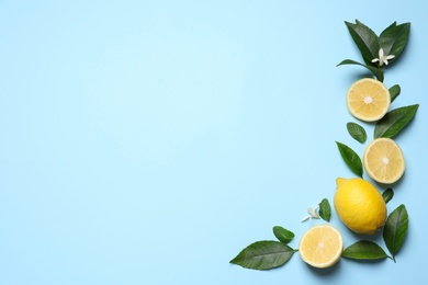 Photo of Many fresh ripe lemons with green leaves and flowers on light blue background, flat lay. Space for text