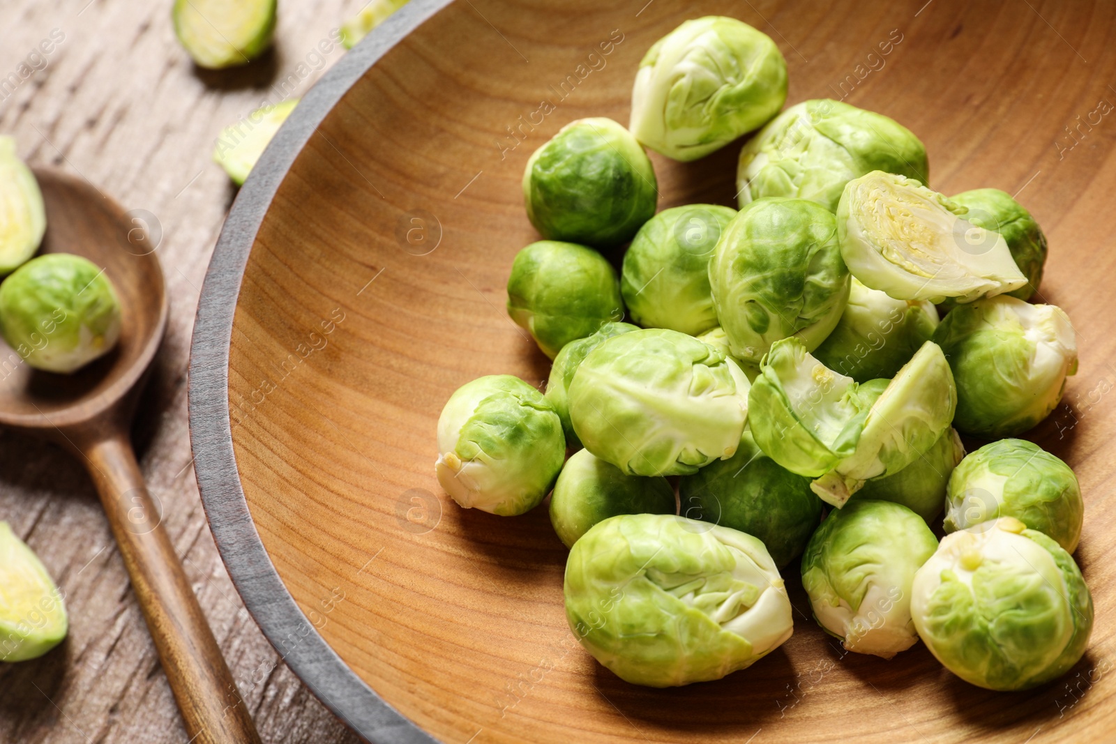 Photo of Bowl with fresh Brussels sprouts on wooden table, closeup