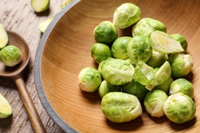 Bowl with fresh Brussels sprouts on wooden table, closeup