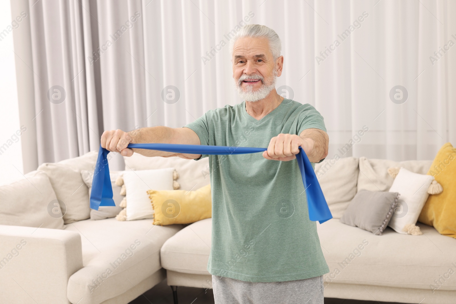 Photo of Senior man doing exercise with fitness elastic band at home