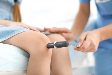 Photo of Children's doctor examining little girl in hospital, closeup