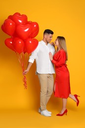 Lovely couple with heart shaped balloons on yellow  background. Valentine's day celebration