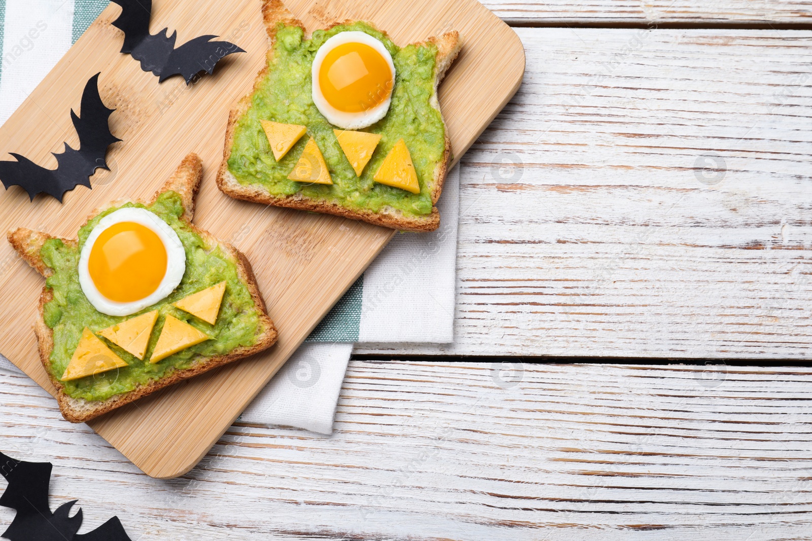 Photo of Halloween themed breakfast served on white wooden table, flat lay and space for text. Tasty sandwiches with fried eggs