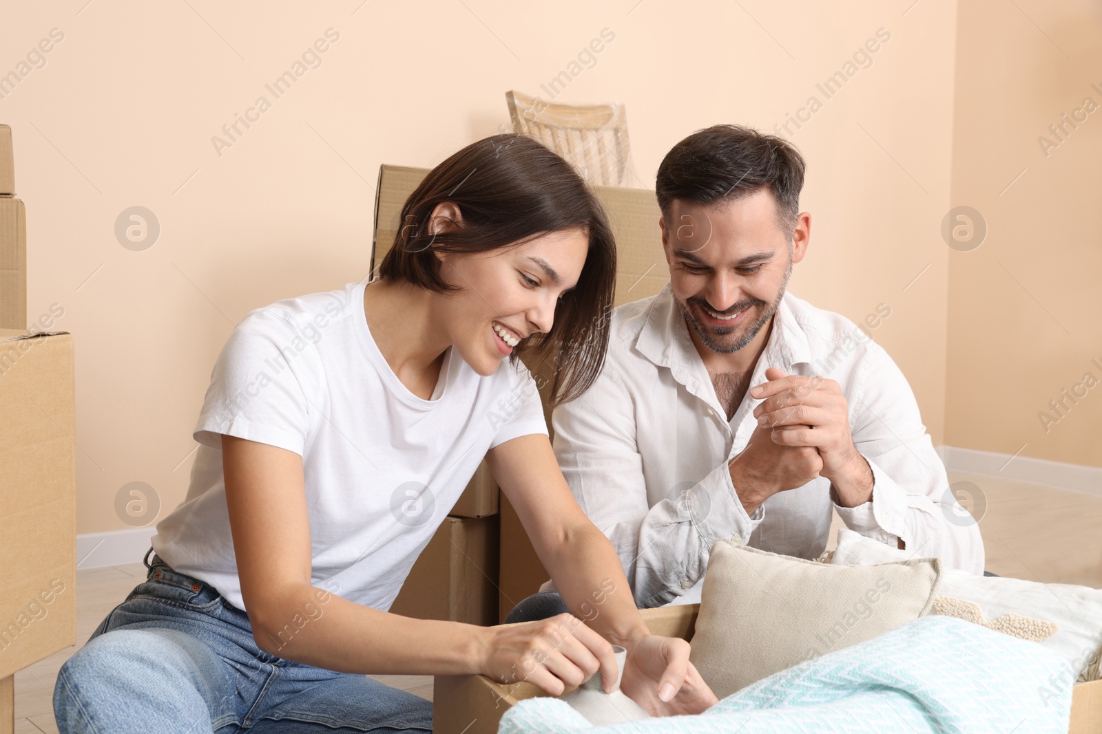 Photo of Happy couple unpacking box in new apartment. Moving day