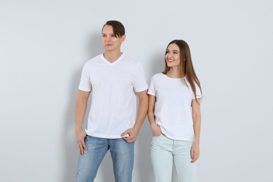 Young couple in stylish jeans on light background