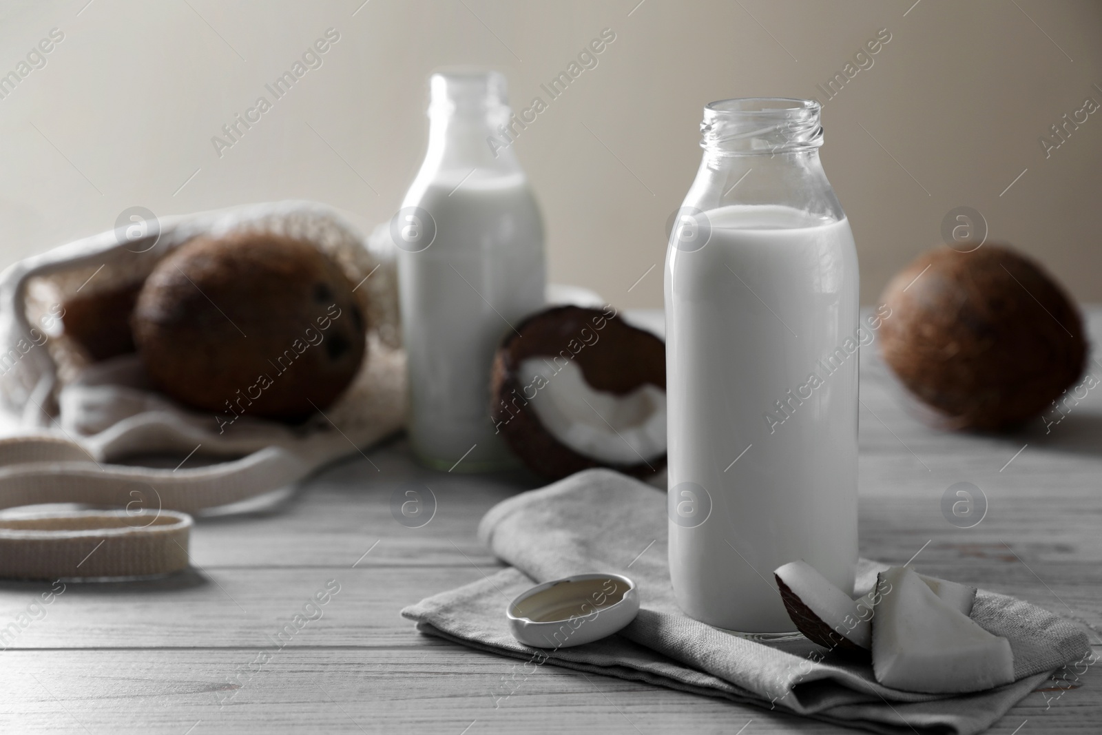 Photo of Coconut milk and nuts on white wooden table, space for text