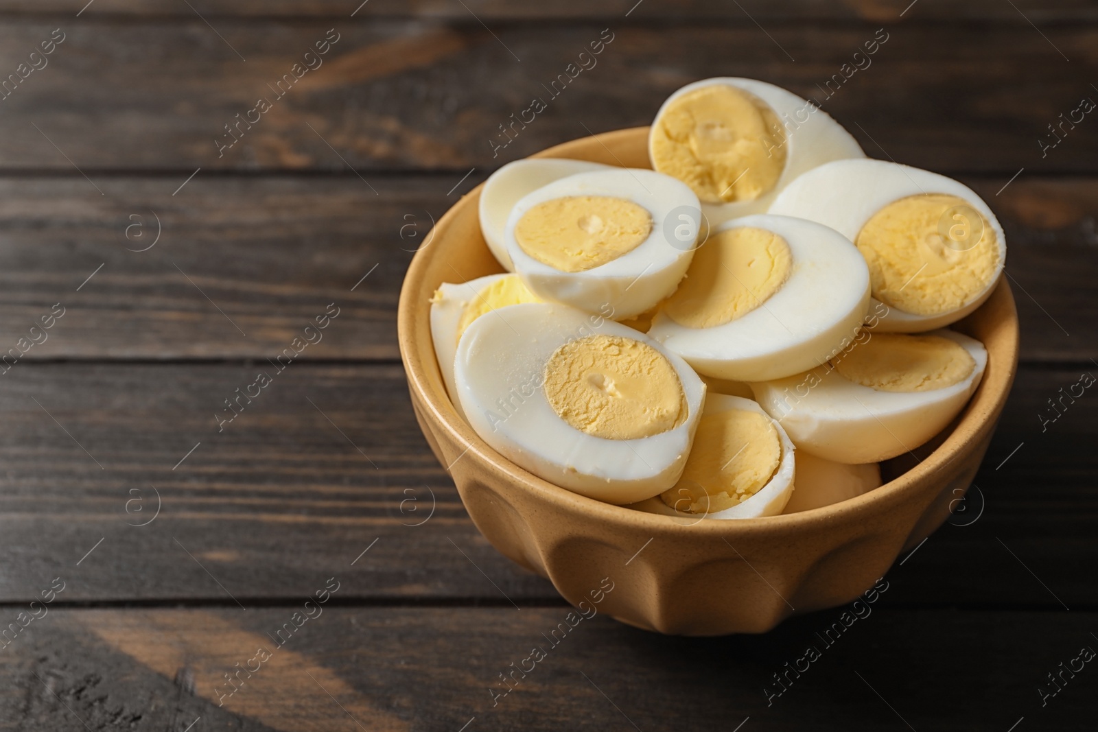 Photo of Bowl with boiled eggs on wooden background. Space for text