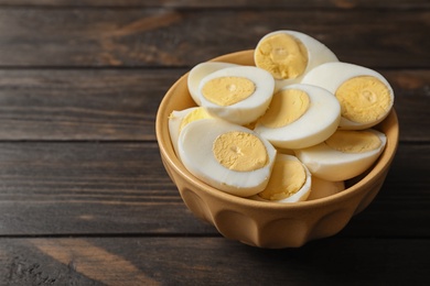 Bowl with boiled eggs on wooden background. Space for text