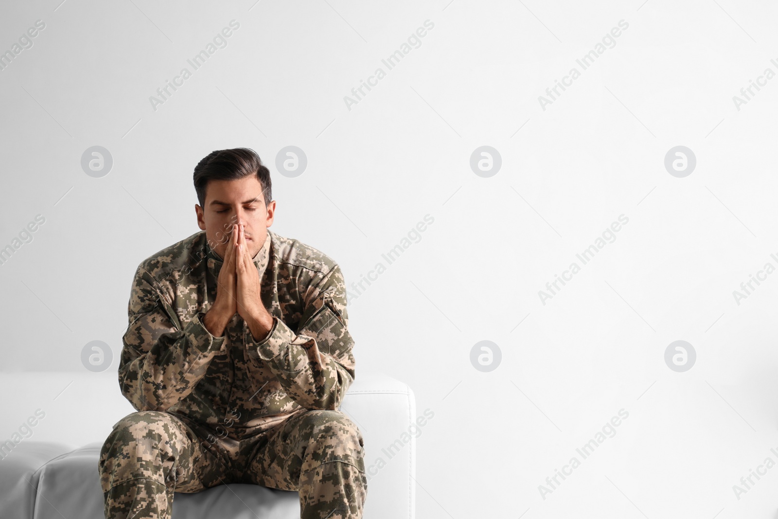 Photo of Stressed military officer sitting on sofa against white background. Space for text