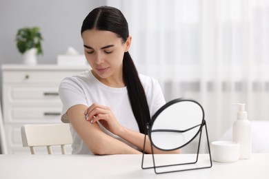 Woman with dry skin looking at mirror indoors