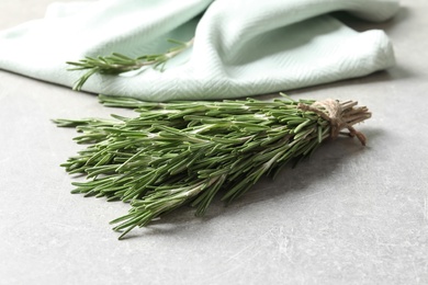 Photo of Fresh rosemary twigs tied with twine on table, closeup