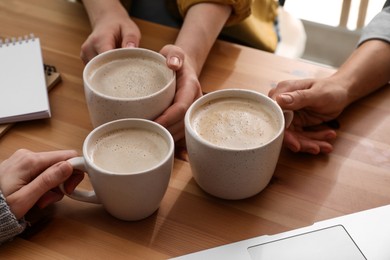 Women with cups of coffee at table in cafe, closeup