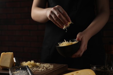 Photo of Woman with grated cheese at wooden table, closeup