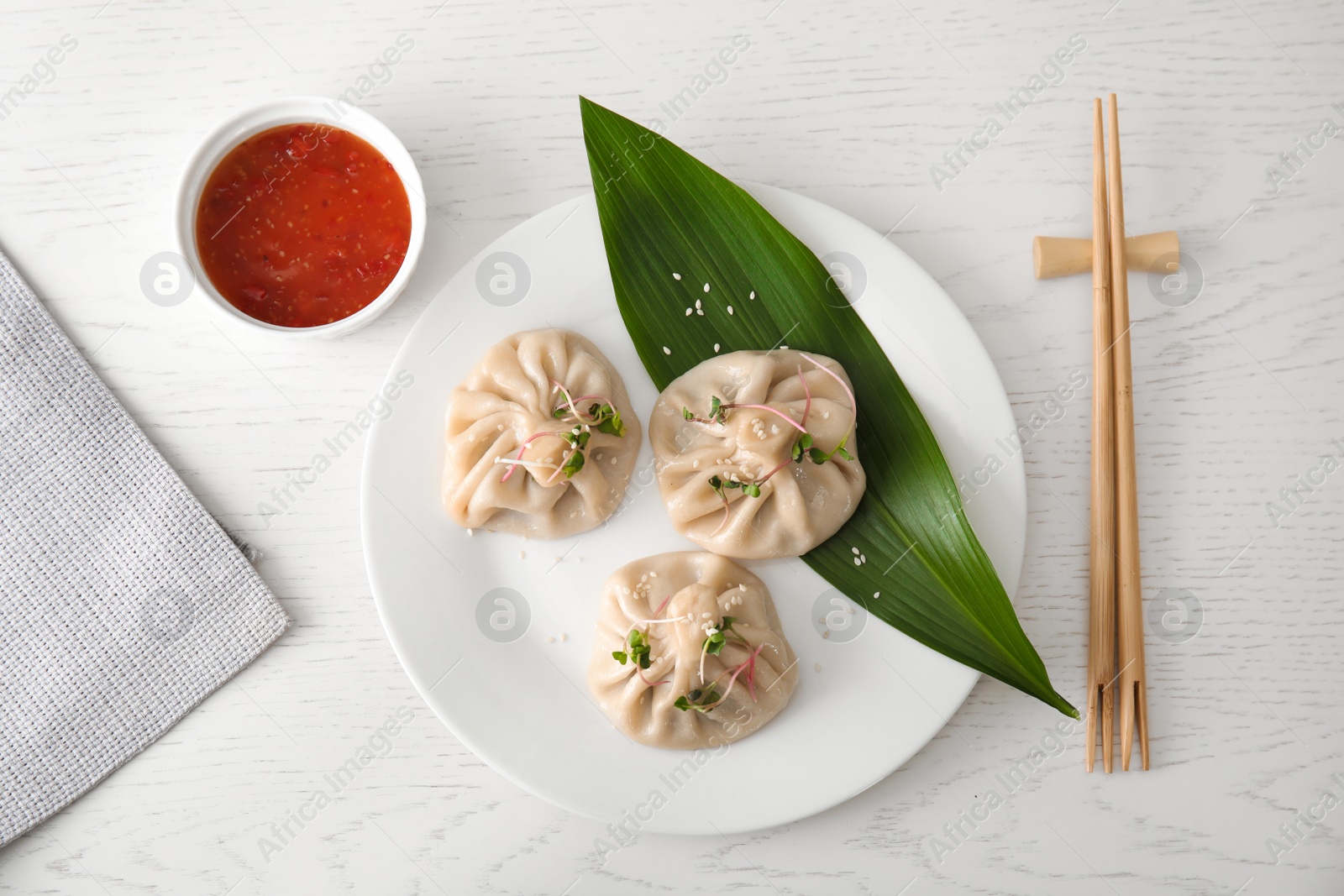 Photo of Plate with tasty baozi dumplings served on white wooden table, top view