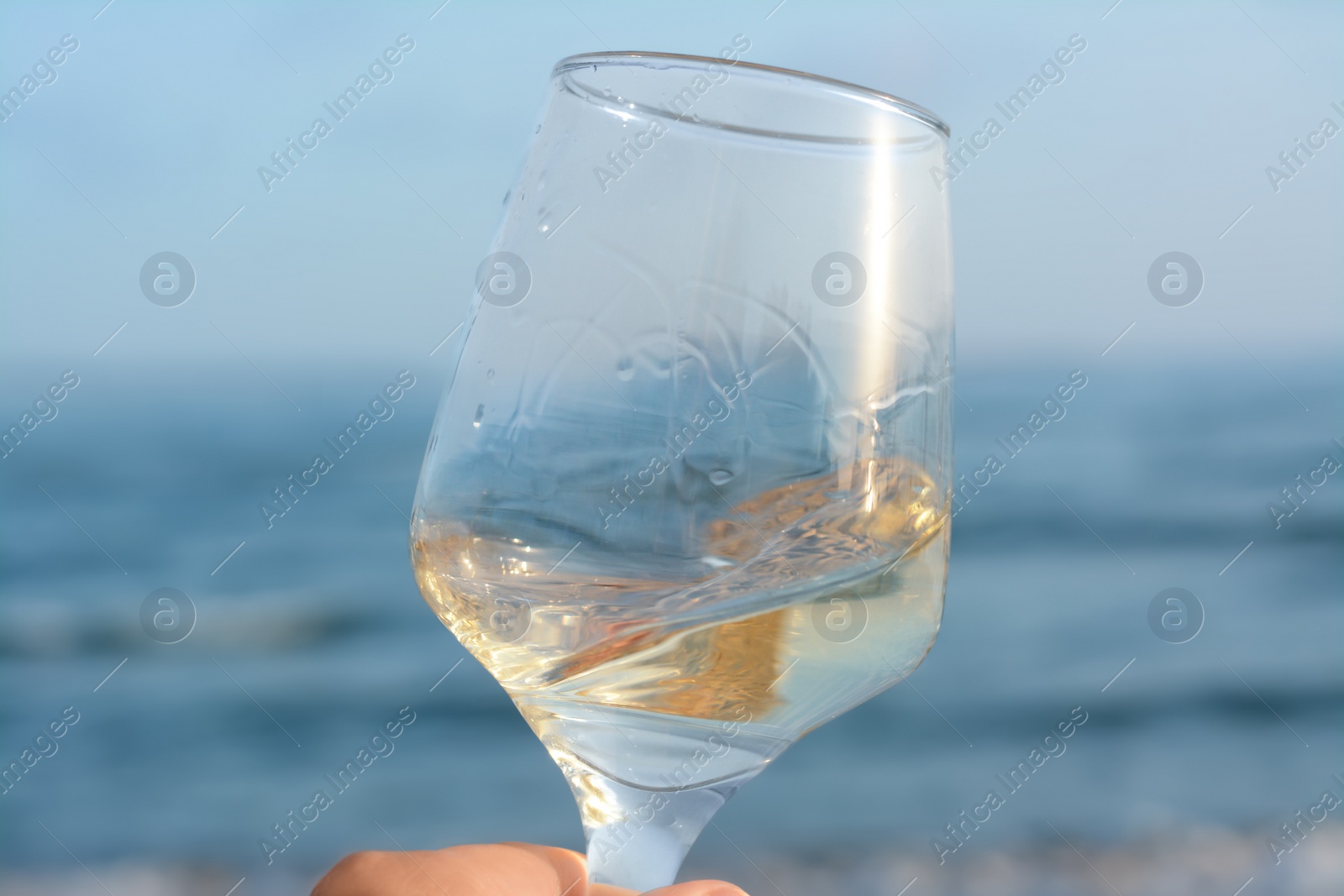 Photo of Glass of tasty wine near sea, closeup