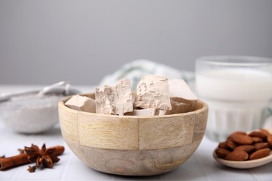 Photo of Wooden bowl with compressed yeast on white tiled table, closeup