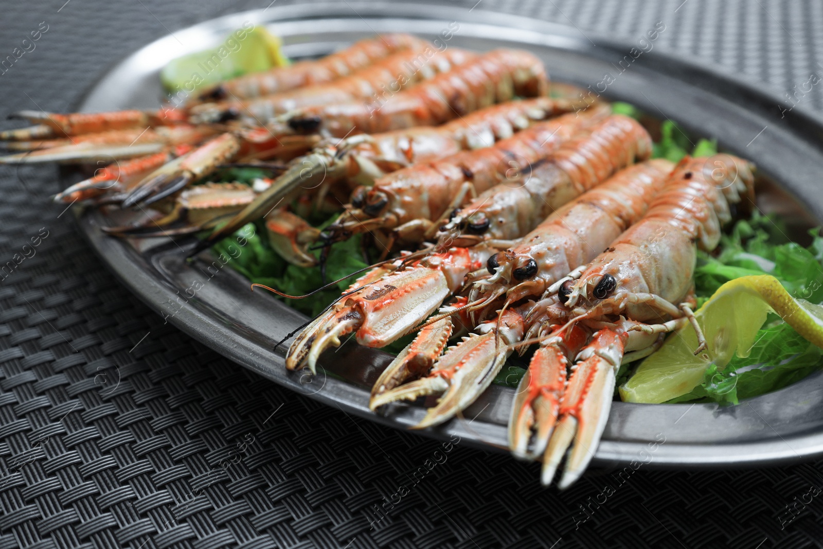 Photo of Plate with tasty boiled crayfish and salad on black table, closeup