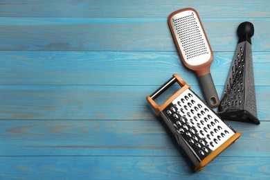 Photo of Different modern graters on light blue wooden table, flat lay. Space for text
