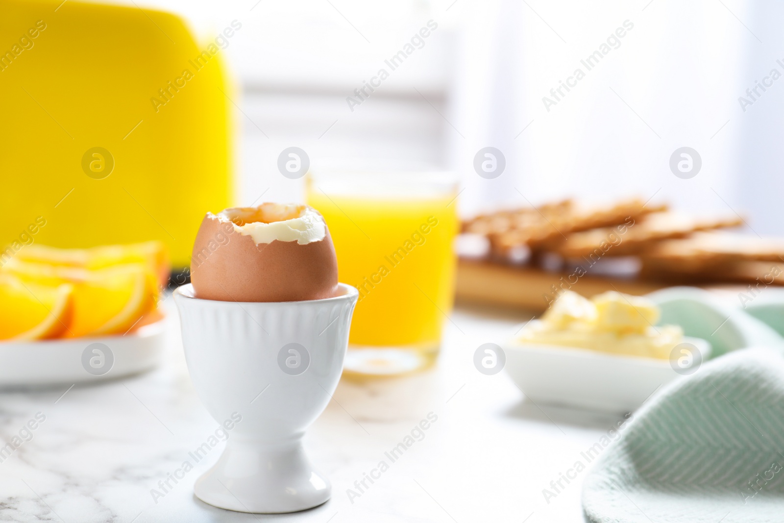 Photo of Cup with soft boiled egg on marble table, space for text. Healthy breakfast