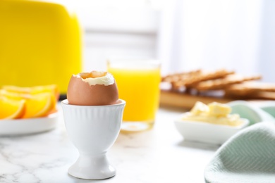 Photo of Cup with soft boiled egg on marble table, space for text. Healthy breakfast